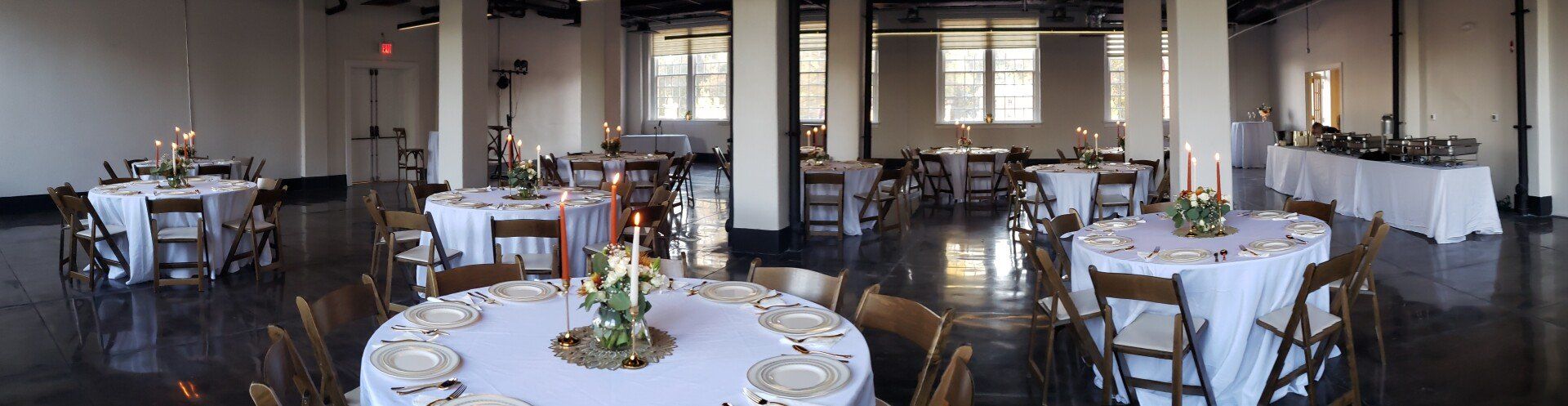 A large room with tables and chairs set up for a wedding reception.