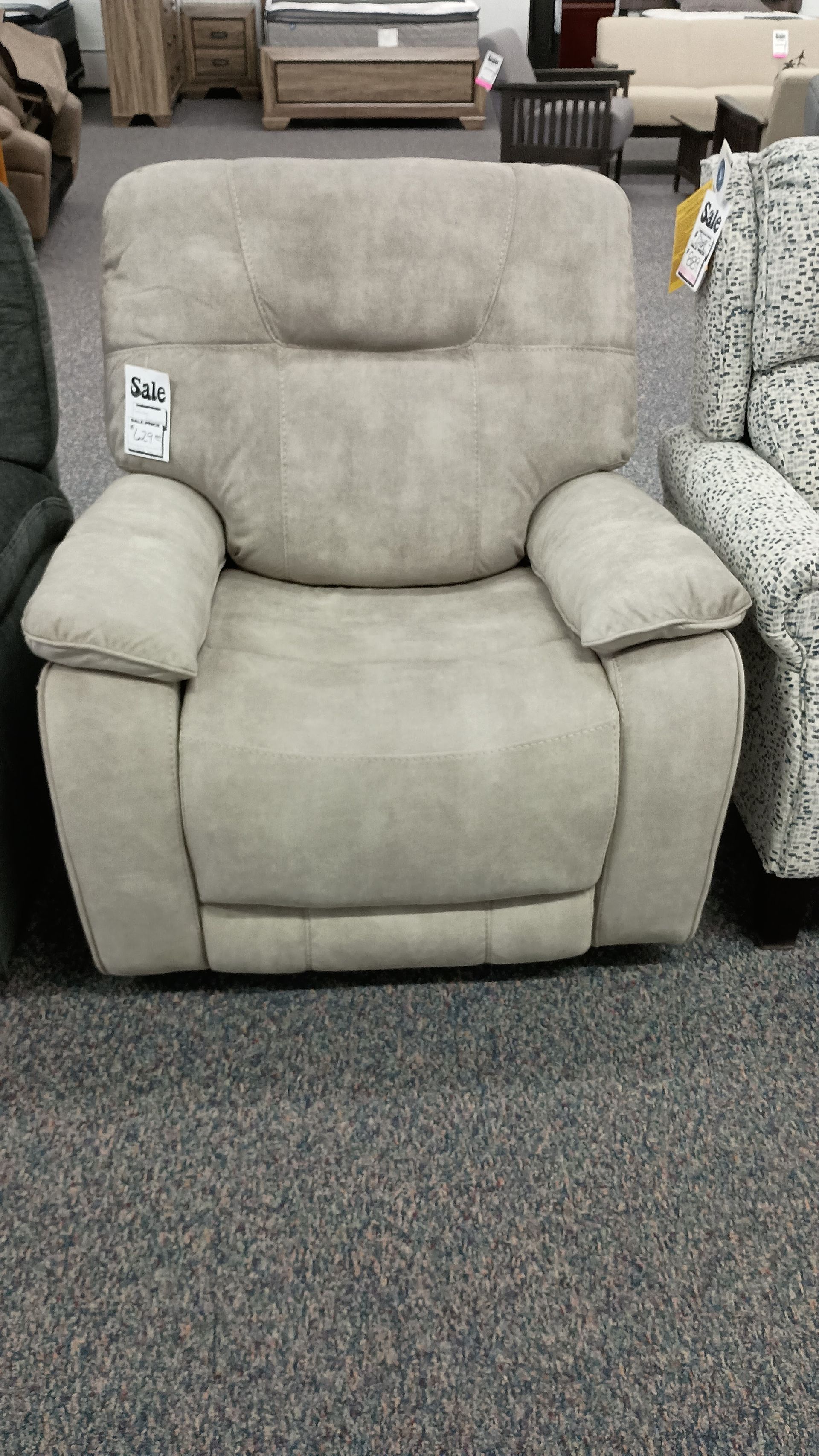 A recliner is sitting on a carpeted floor in a store.