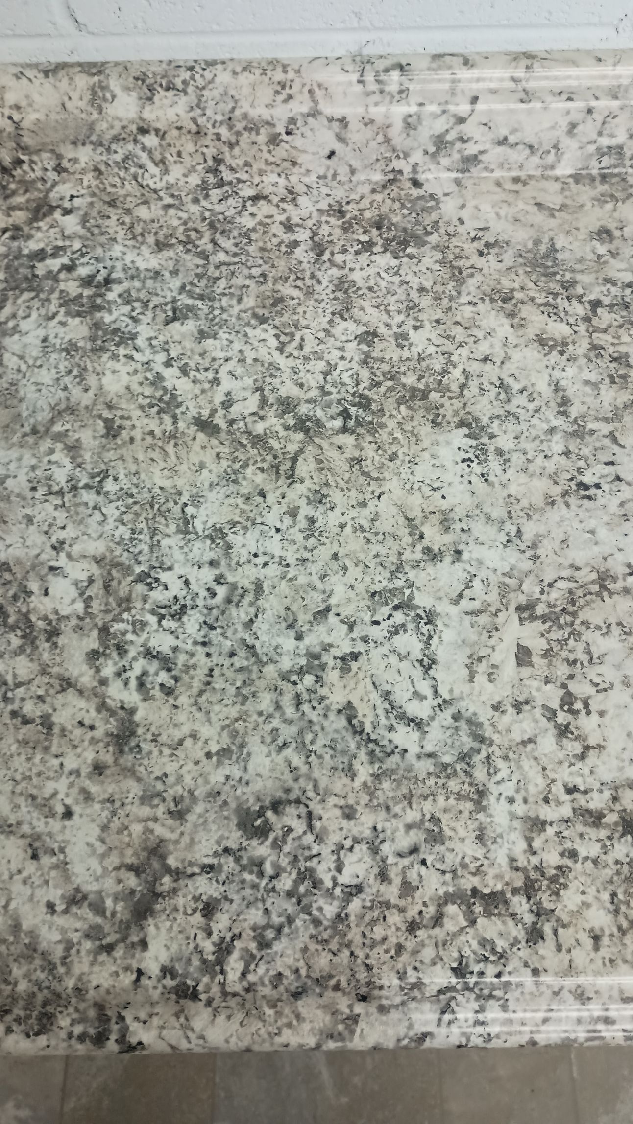White countertop with gray and black speckles.