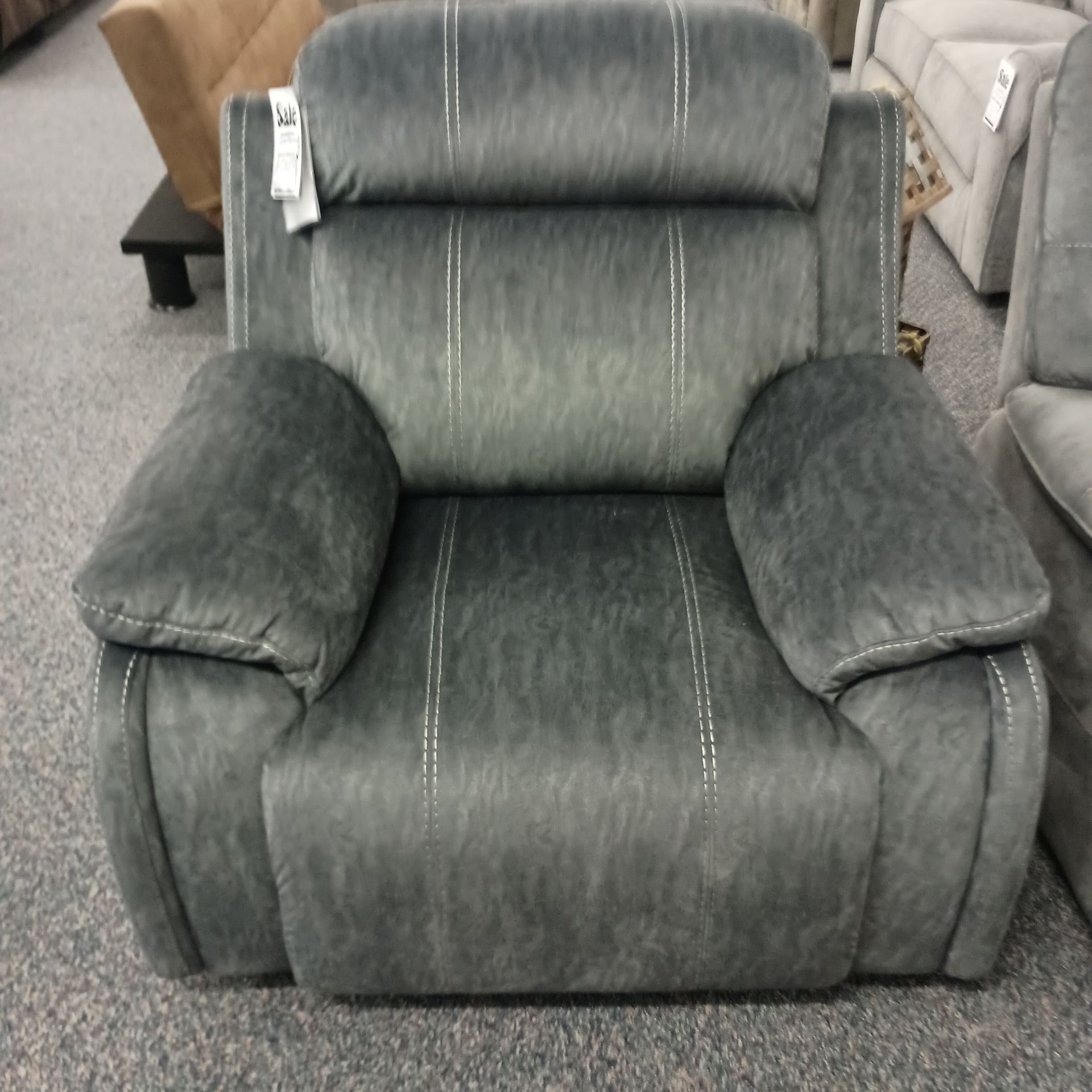 Gray recliner chair with padded arms and headrest, detailed with white stitching.