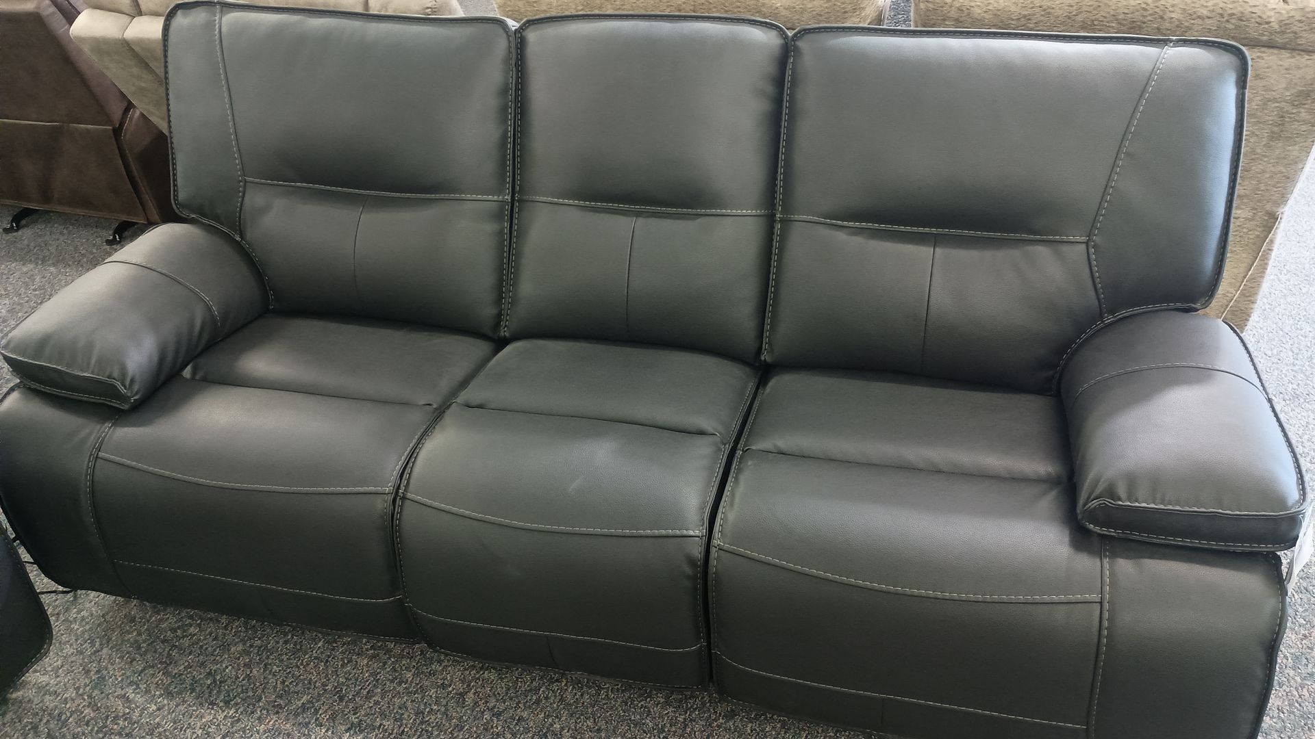 Dark gray leather reclining sofa with three seats.