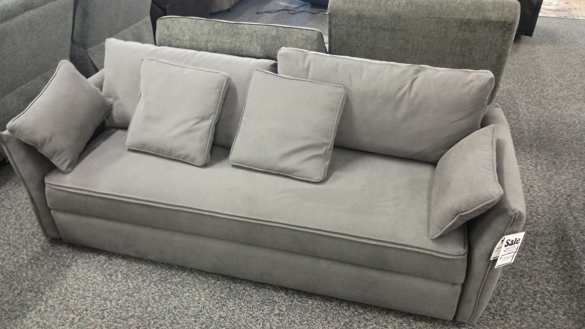 Gray upholstered sofa with three back cushions and two side cushions