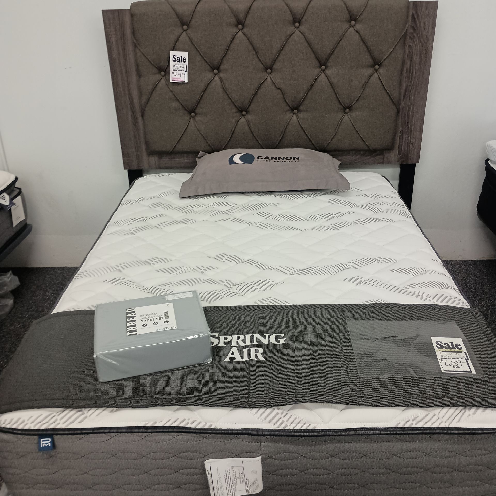 A single bed with a tufted headboard and a Spring Air mattress.