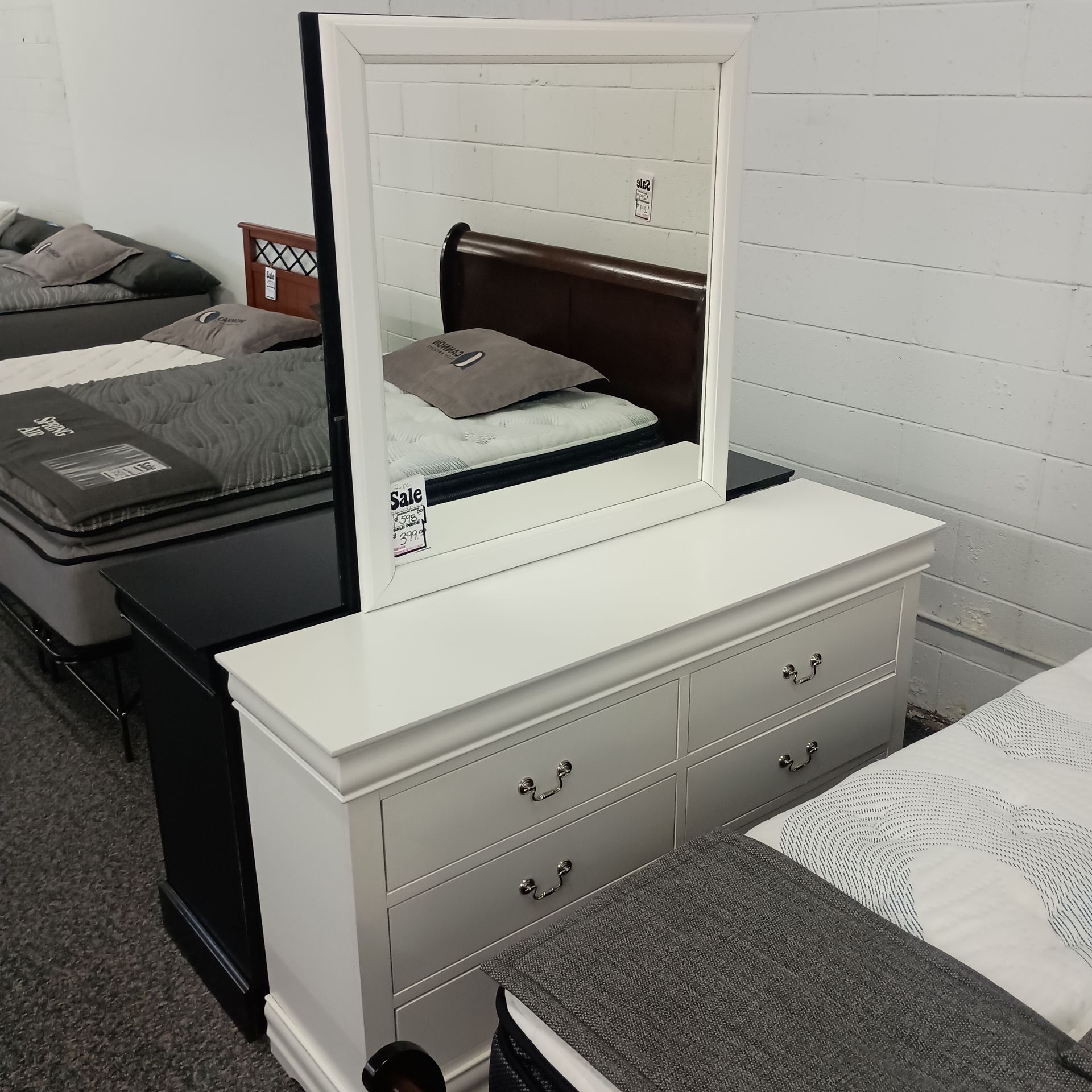 White dresser with attached mirror, bedroom furniture display.