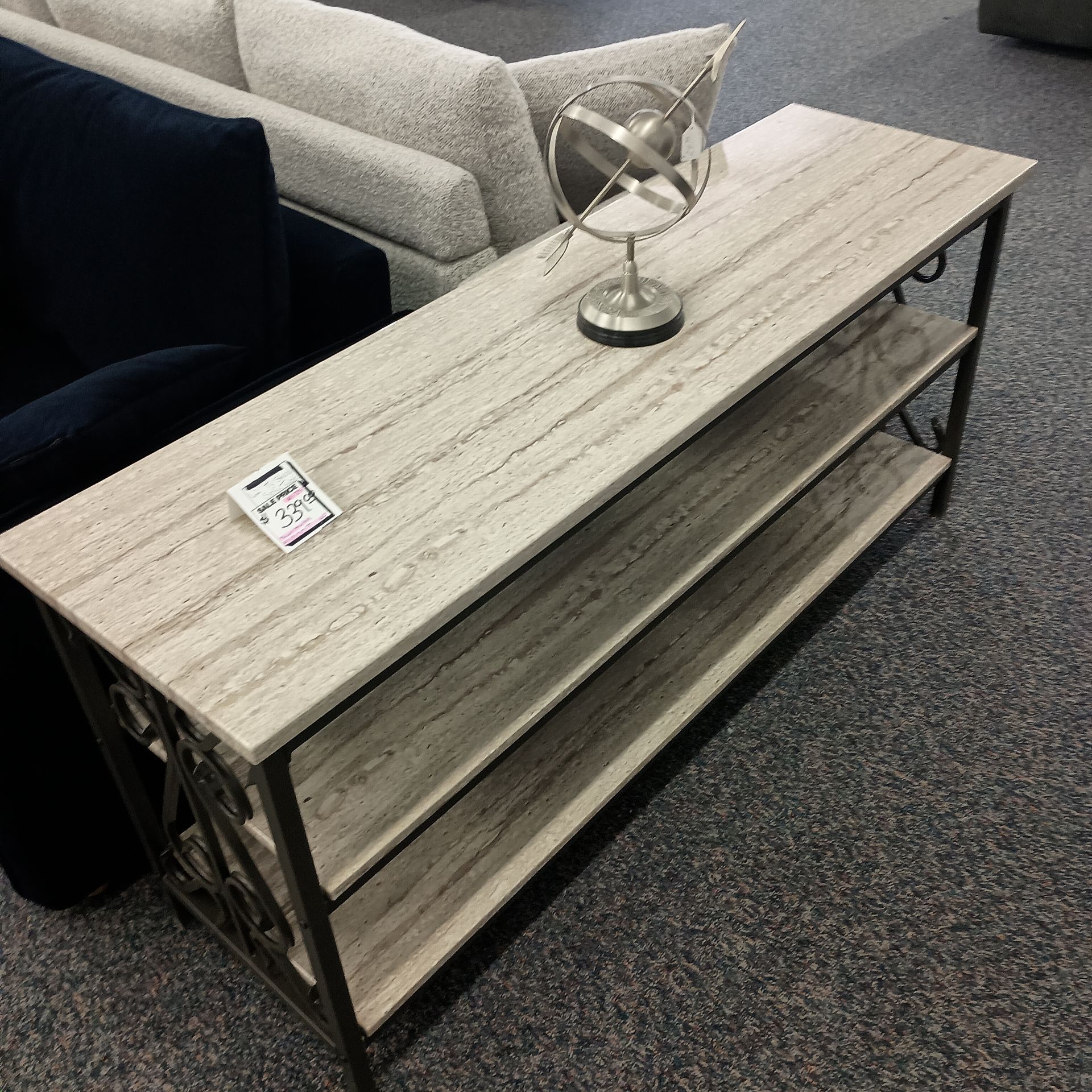 Long, narrow, gray wood console table with metal frame and three shelves; globe decoration on top.