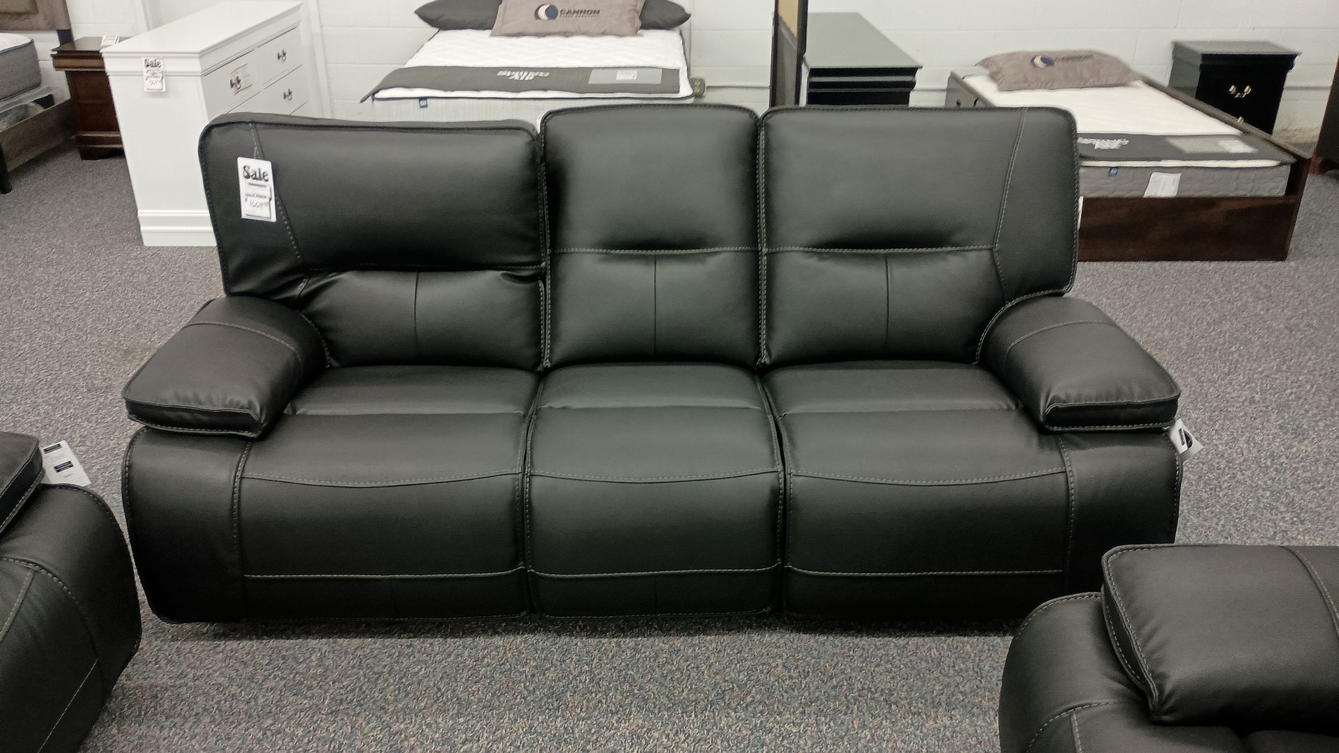 A black leather couch with a price tag on it