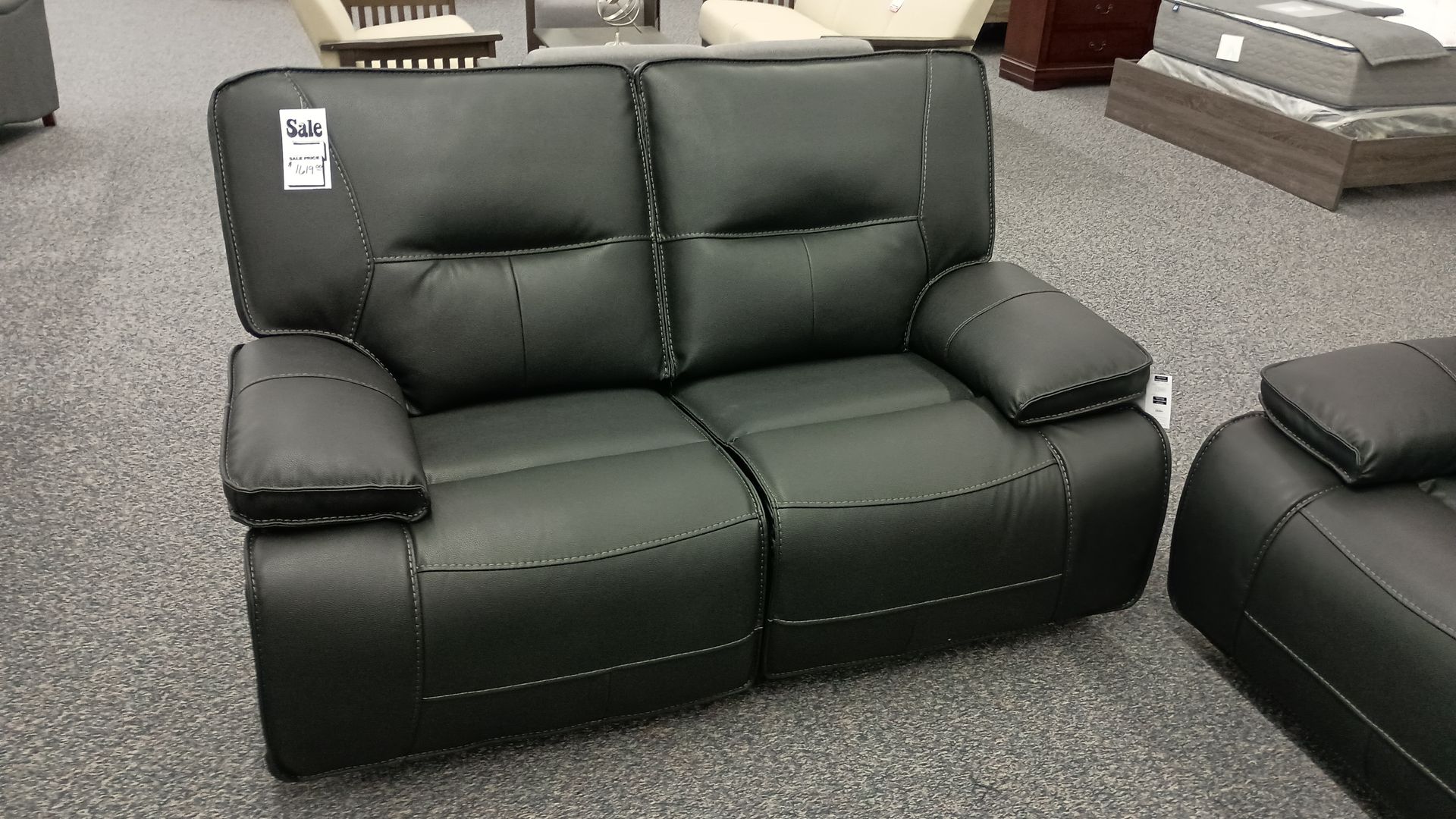 A black leather couch with a price tag on it