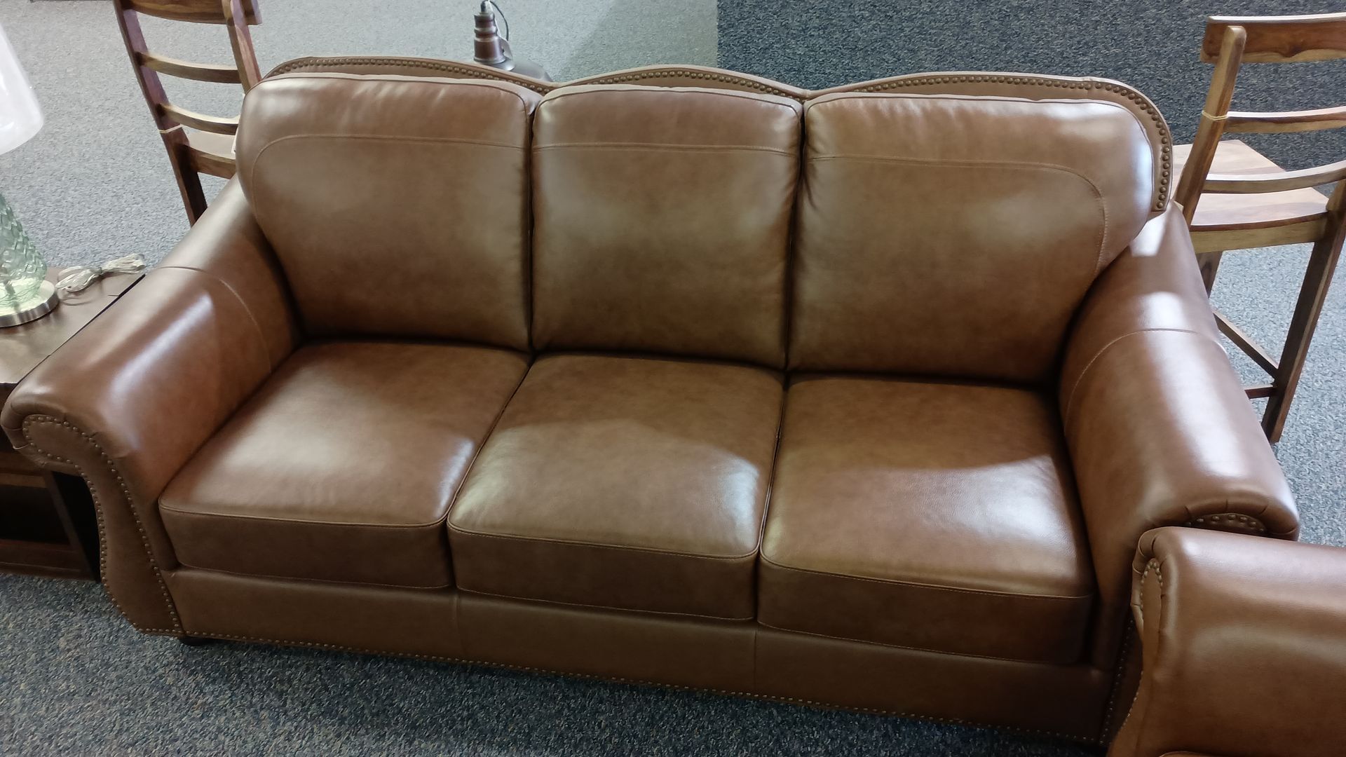 A brown leather couch is sitting on a carpeted floor