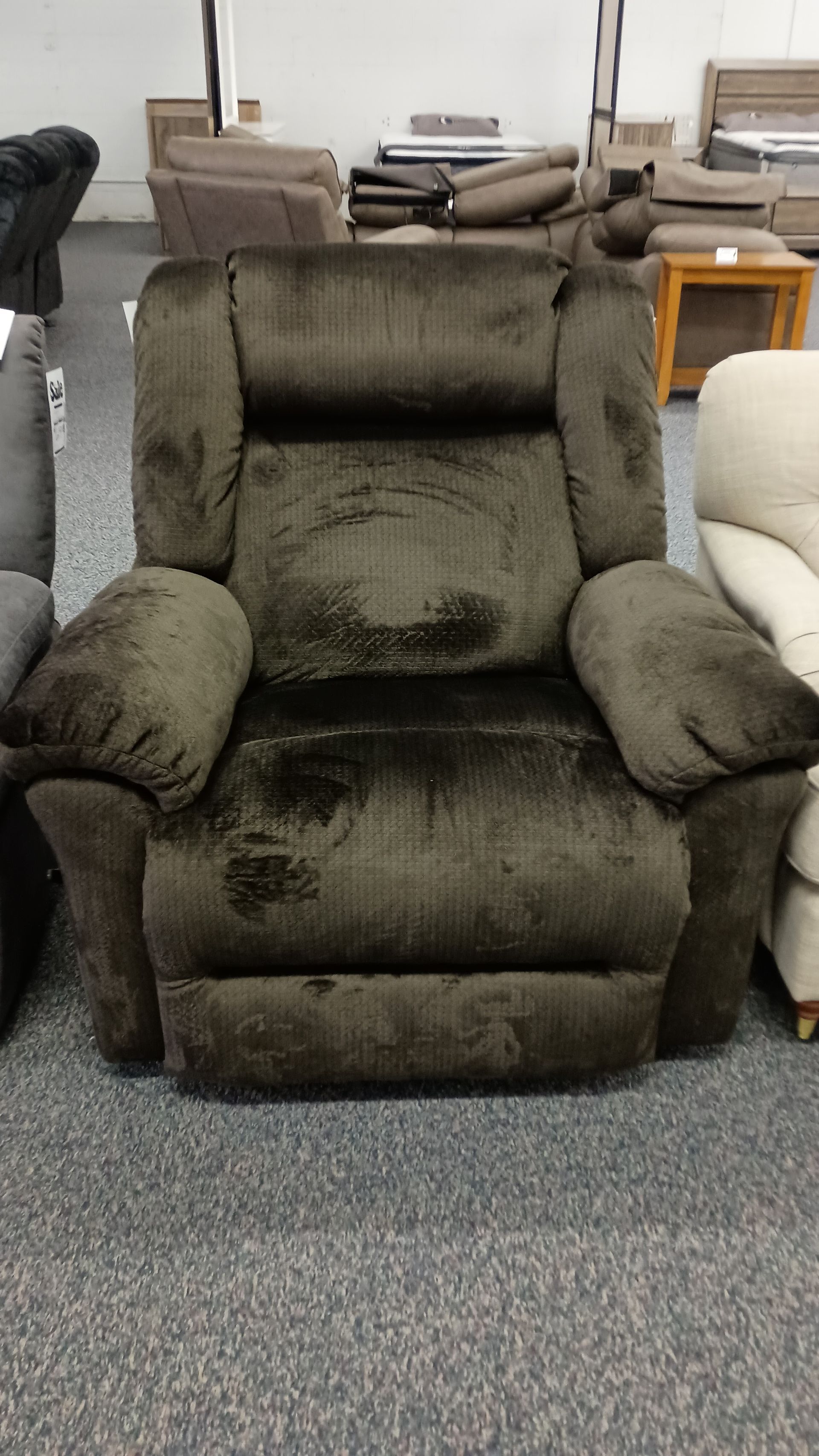 A brown recliner is sitting in a room with other chairs.