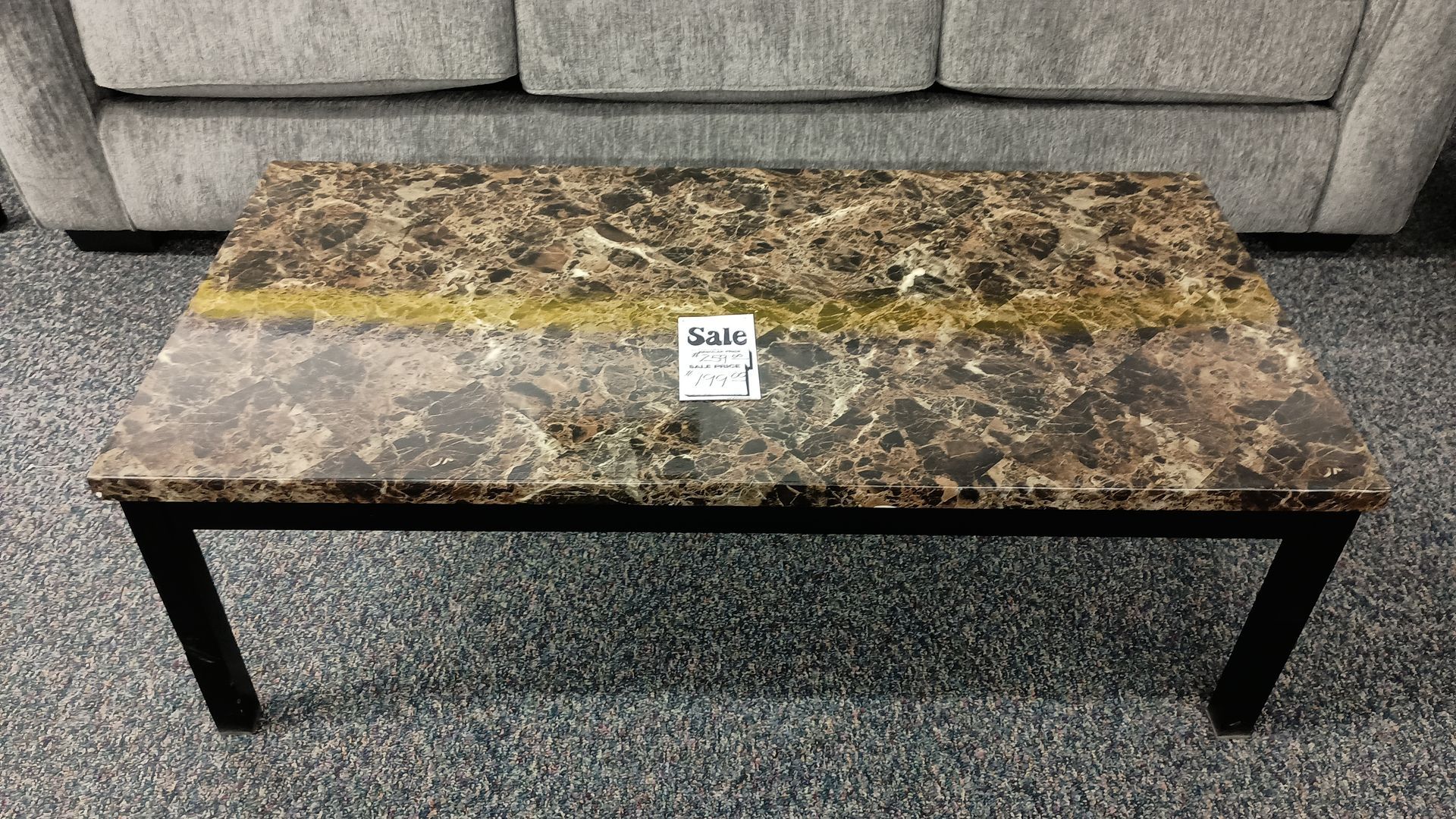 A coffee table with a marble top sits in front of a couch