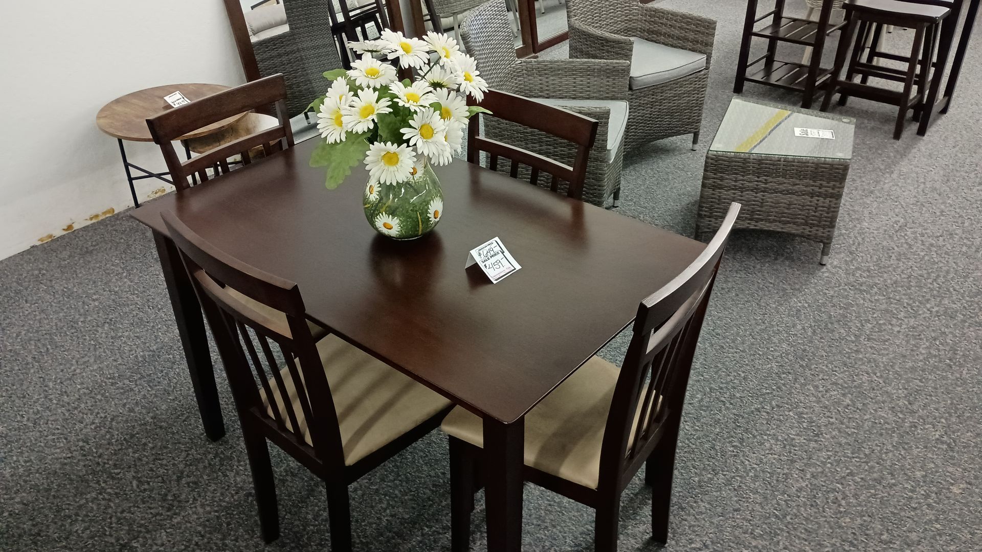 A table with four chairs and a vase of flowers on it