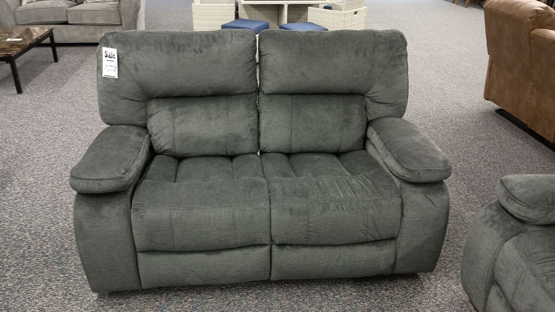A grey recliner couch is sitting on a carpeted floor in a living room.