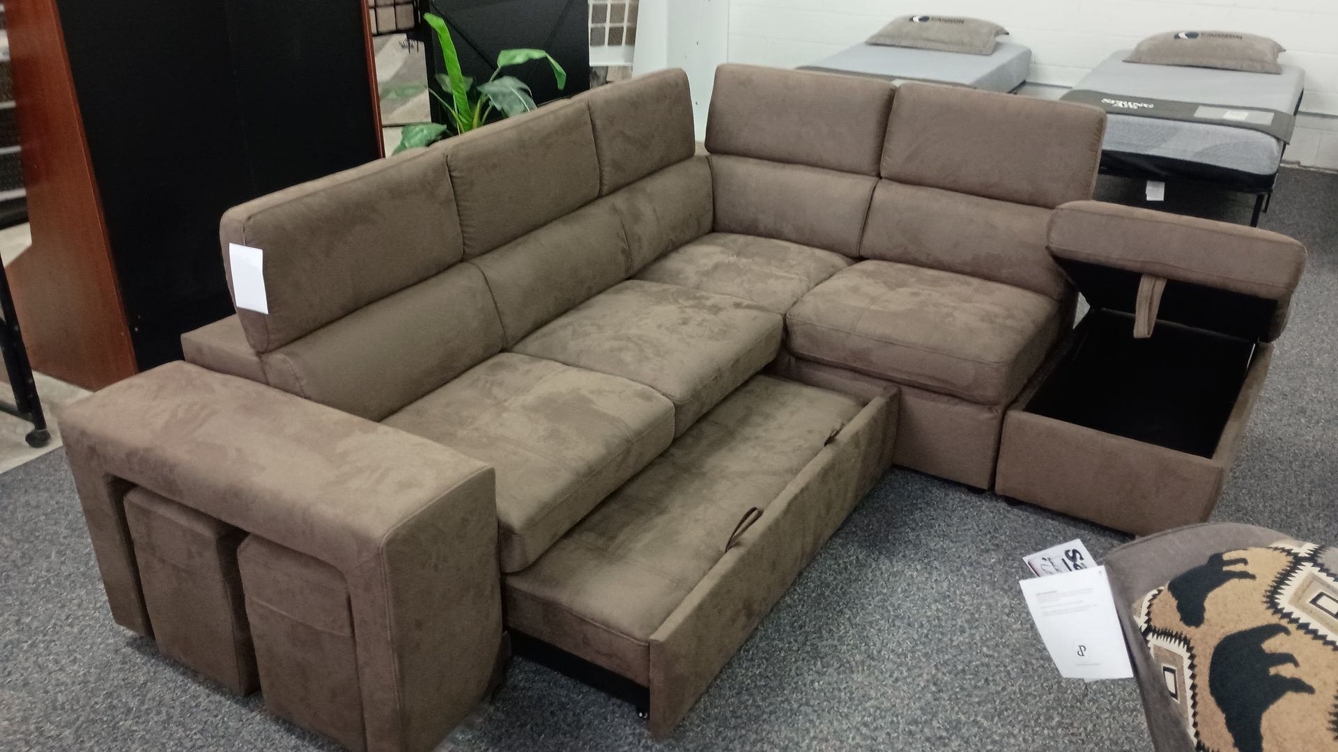 A brown sectional couch with drawers underneath it