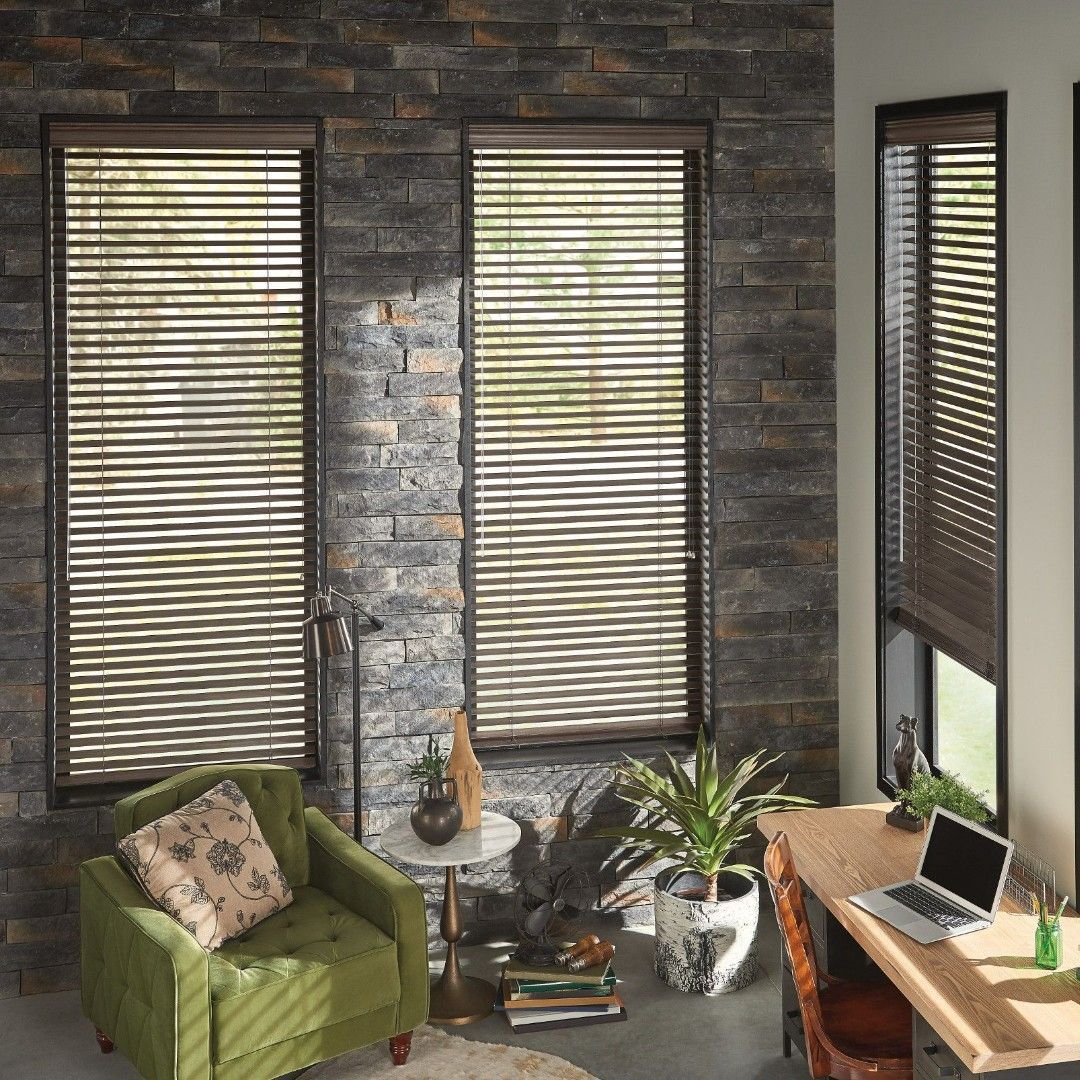 A living room with a green chair and a laptop on a desk