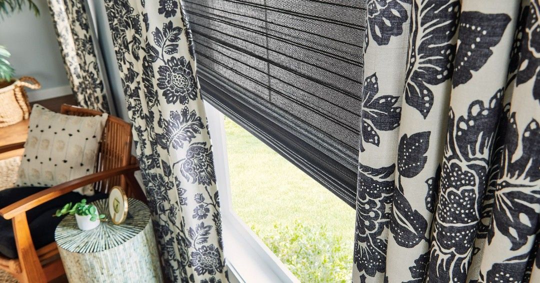 A living room with black and white curtains and a chair.