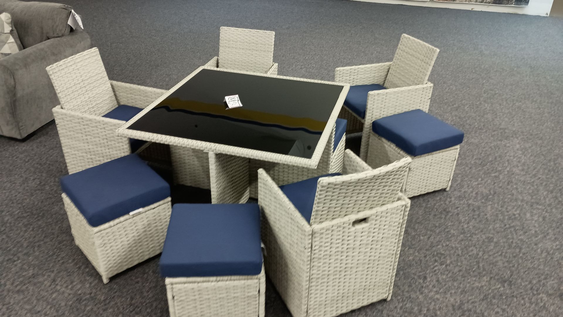 A wicker table and chairs set with blue cushions