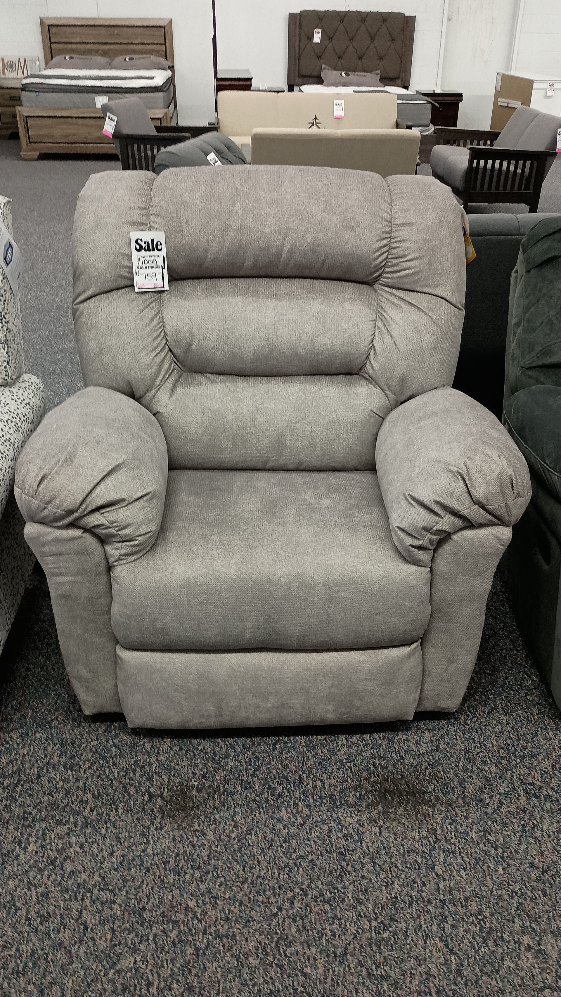 A recliner is sitting on a carpet in a store.