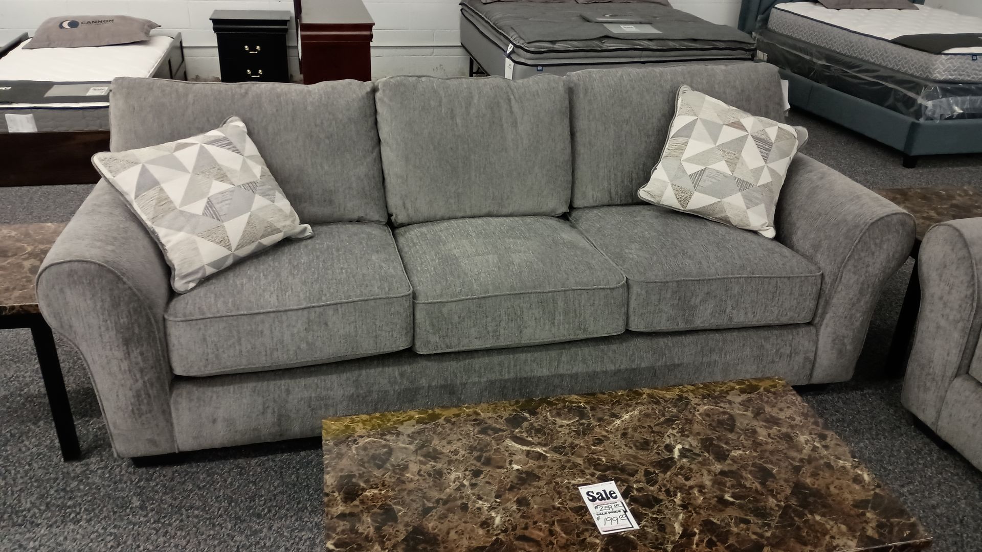 A grey couch with white pillows sits next to a coffee table