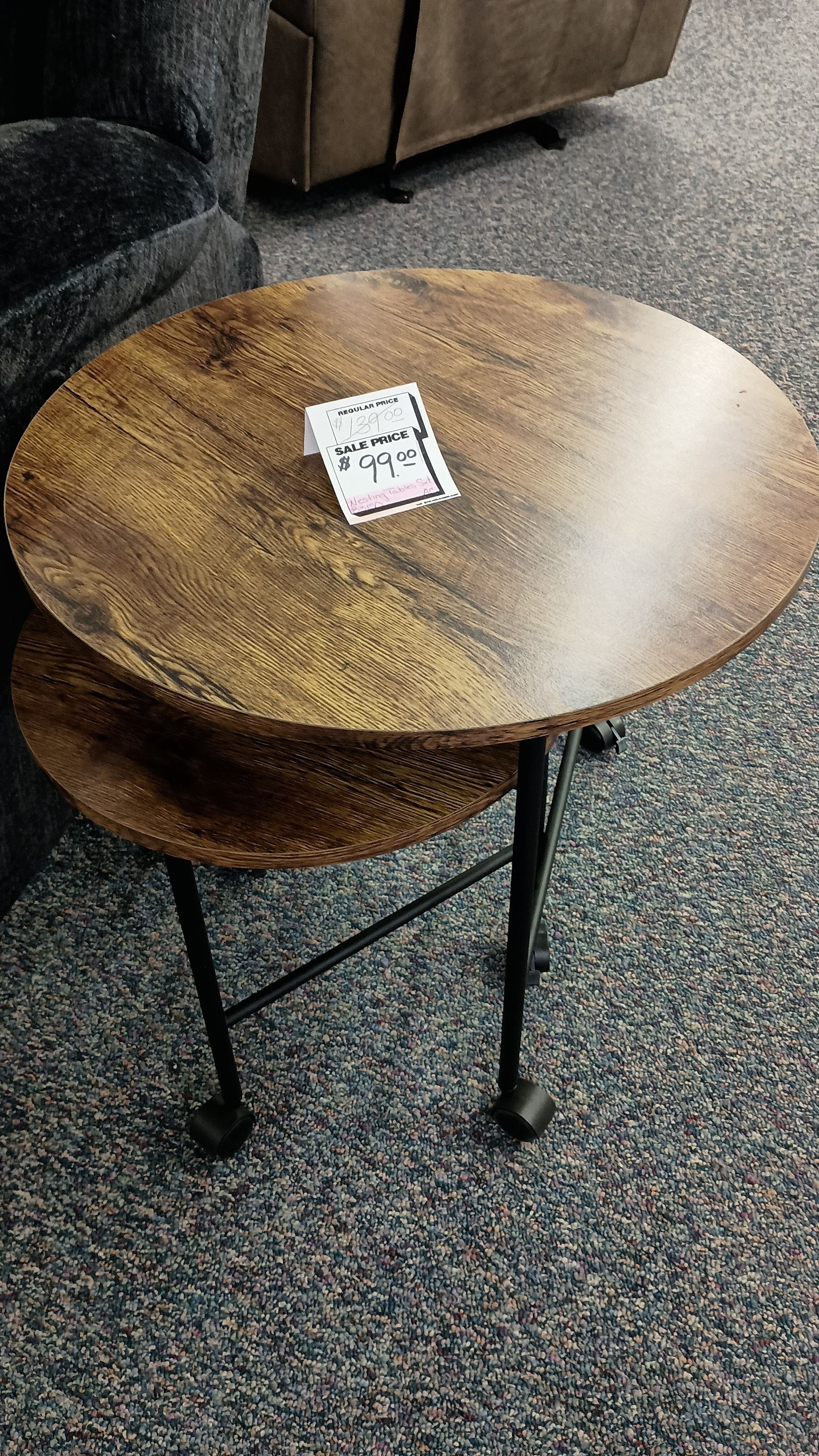 A small wooden table with a tag on it is sitting on a carpeted floor.