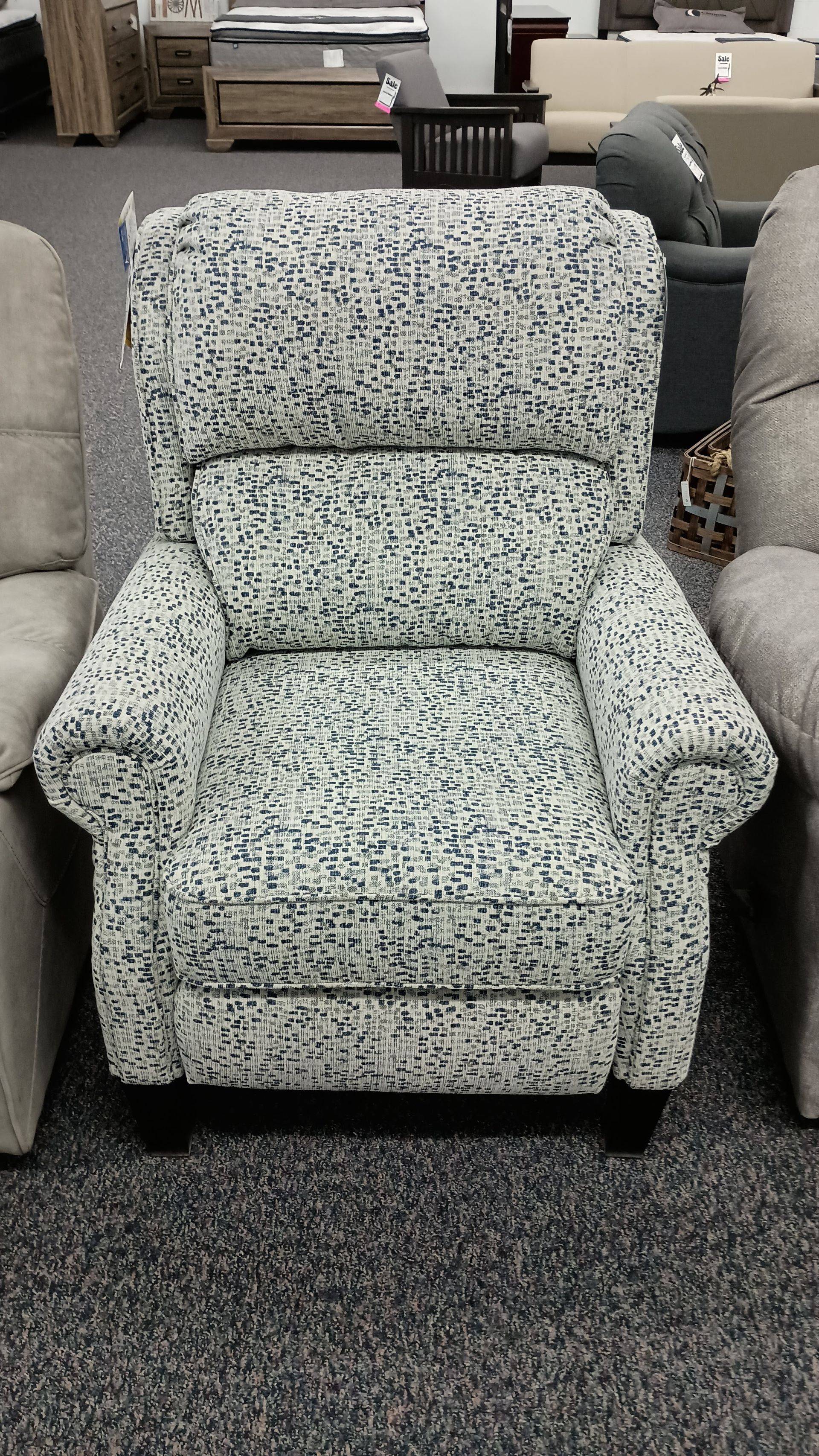 A chair with a pattern on it is sitting on a carpeted floor in a room.