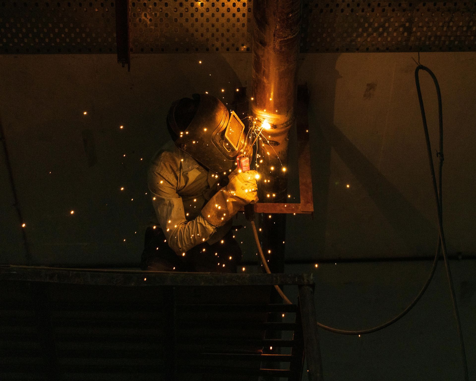 Image of a person welding, emitting bright yellow sparks.