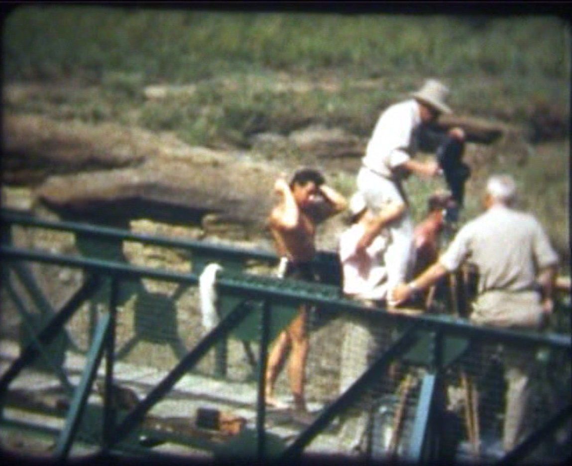 Gordon Scott combing his hair, while the crew prepares a scene on a bridge