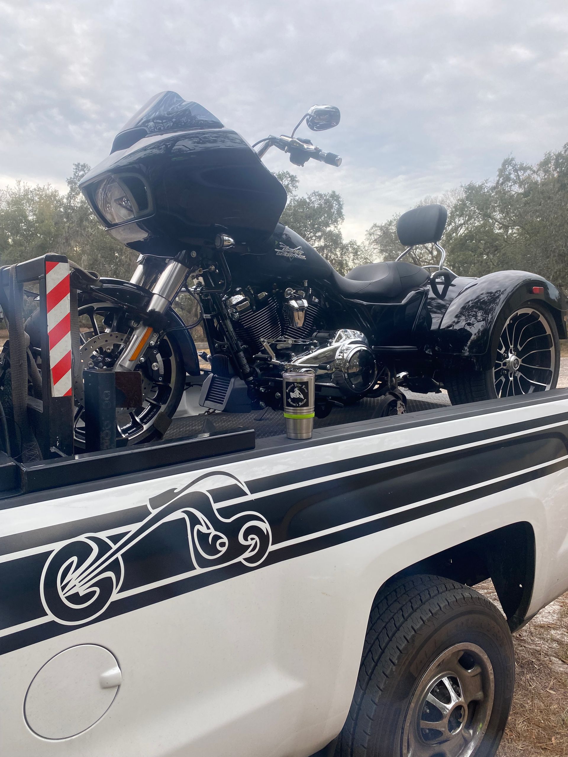 Silver Can-Am Spyder motorcycle on a trailer in a suburban neighborhood.