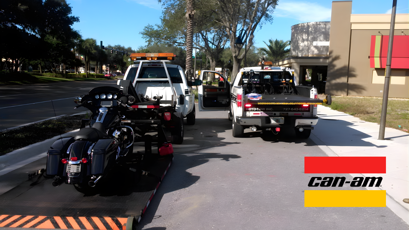 Motorcycle loaded onto a tow truck, with two other trucks nearby. The scene is outdoors near a building.