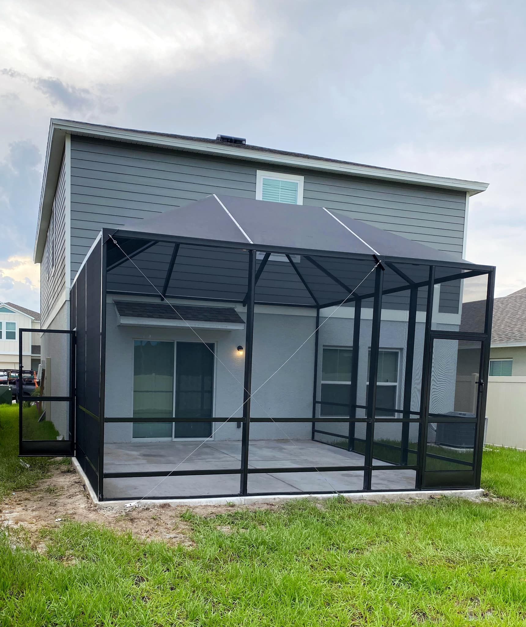 Sunroom with a glass roof and walls, furnished with a dining table, chairs, and a grill.