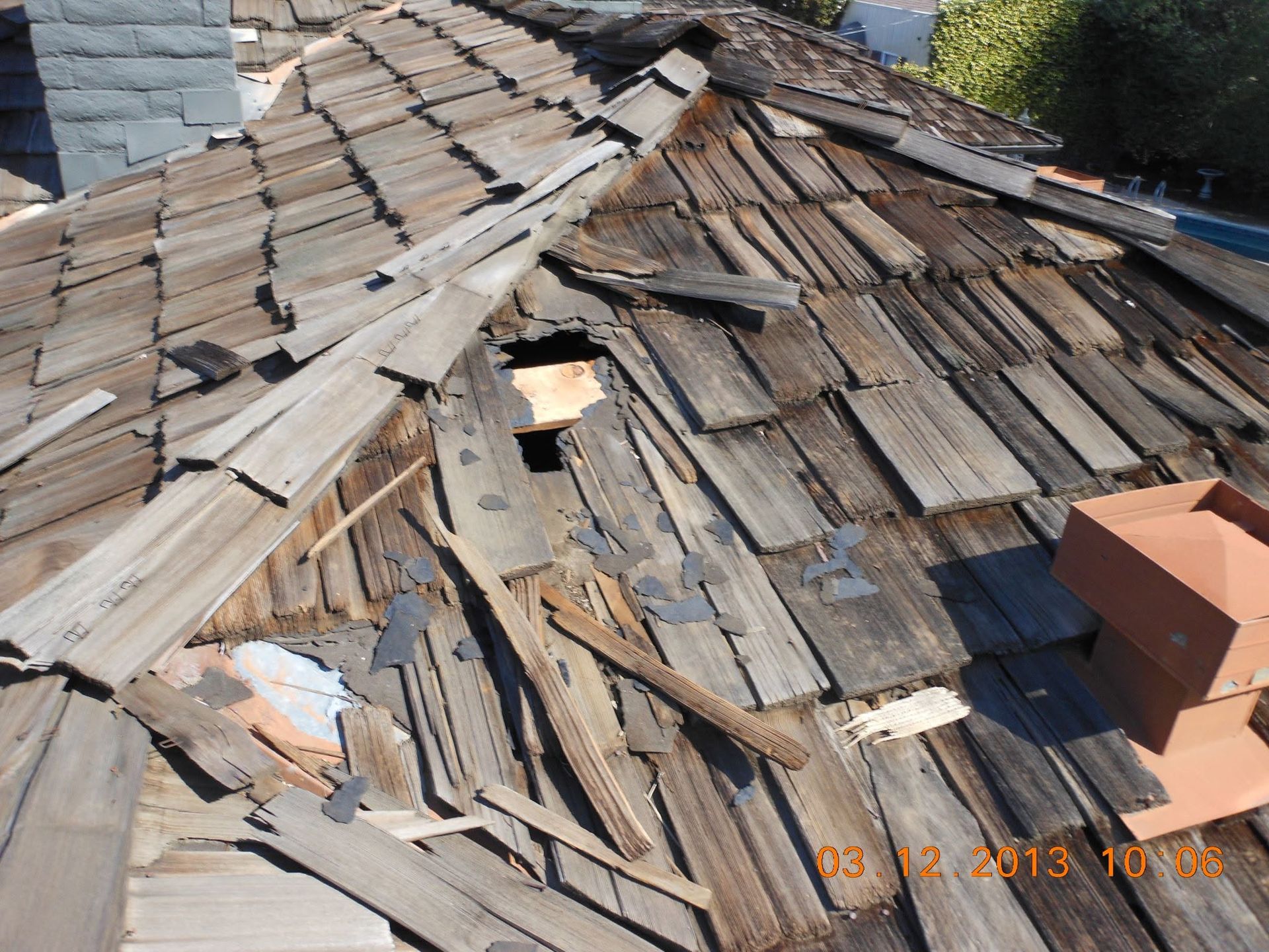 Collapsed weathered shingle roof with missing boards and debris visible on top
