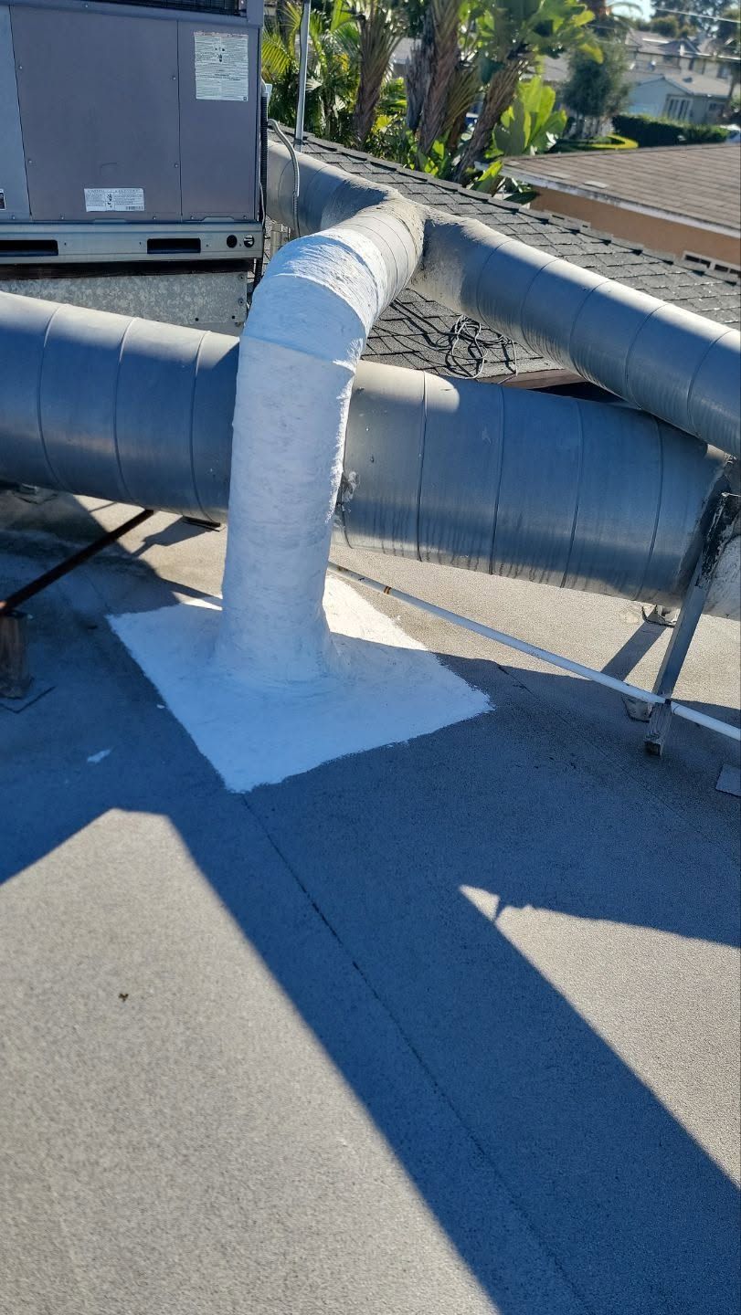 White pipe vent on a flat rooftop, casting a shadow in bright sunlight.