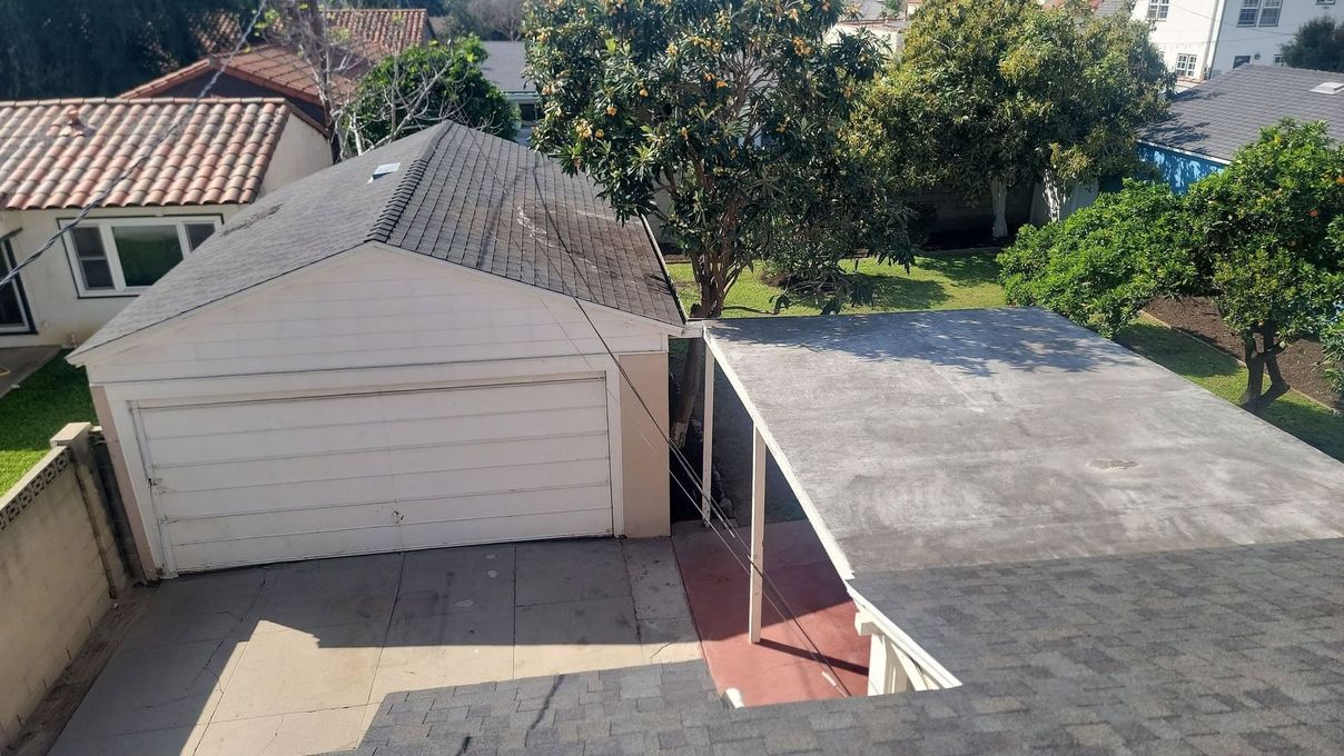White garage beside a flat-roof carport in a residential backyard, viewed from above