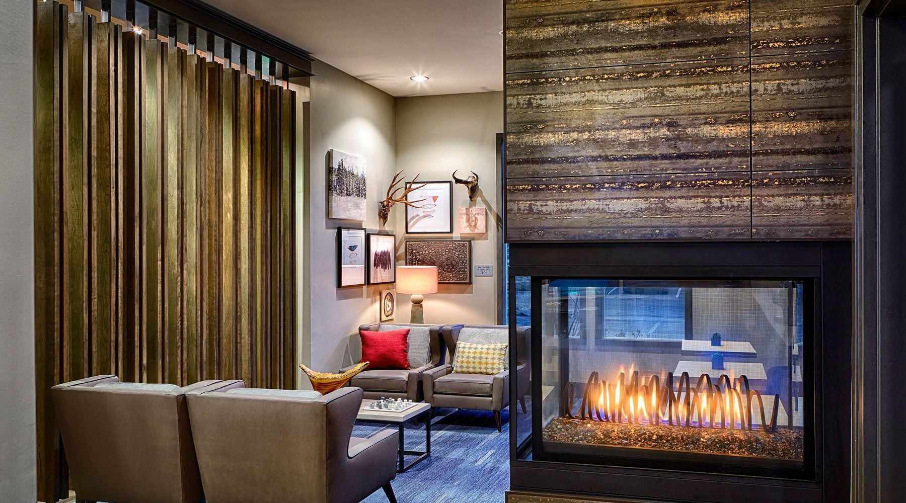 Cozy living room with fireplace, gold curtains, framed art, and seating area with a small table.