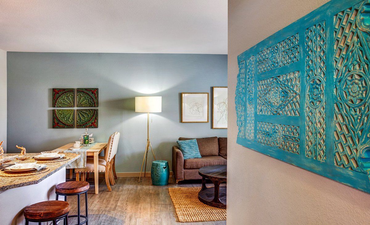 Living room with blue walls, artwork, sofa, dining table, and bar.