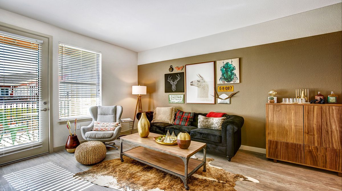 Living room with a sofa, armchair, coffee table, and wood cabinet, decorated with art.
