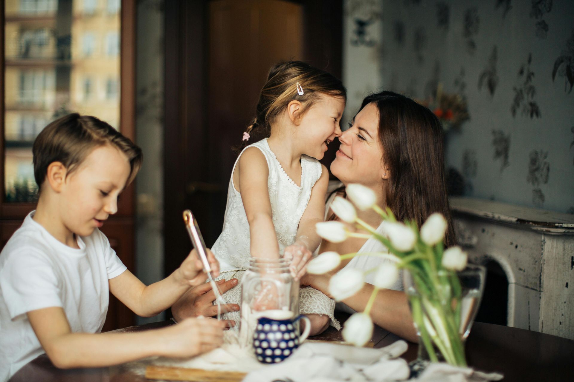 A young boy and girl are sitting at a table with their mother
