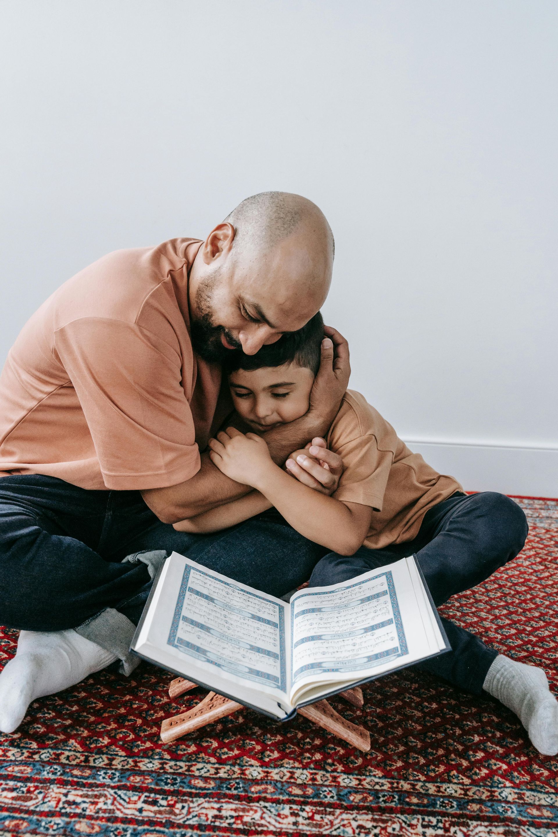 A man hugging a boy while looking at a book