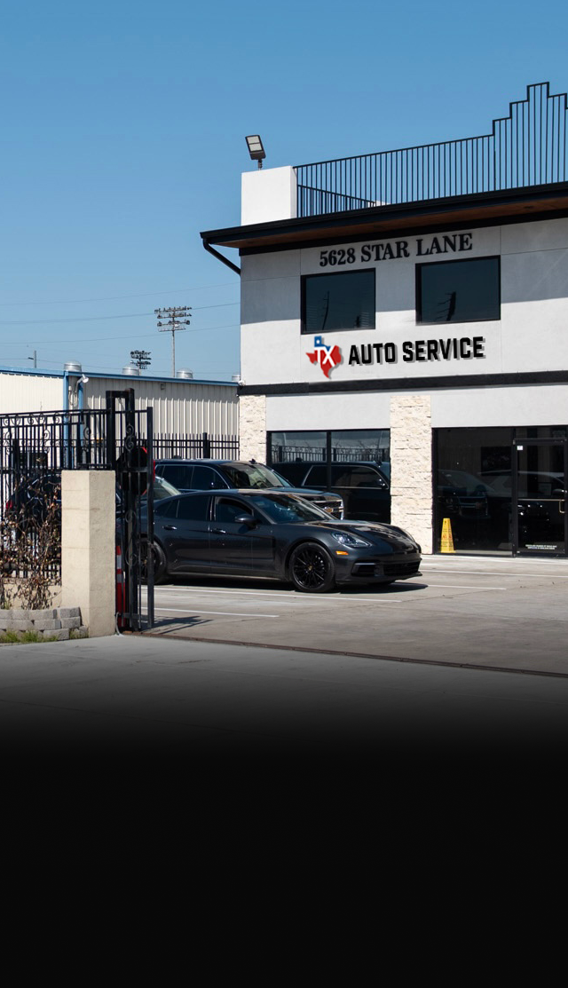A gray Porsche parked in front of a white building with 