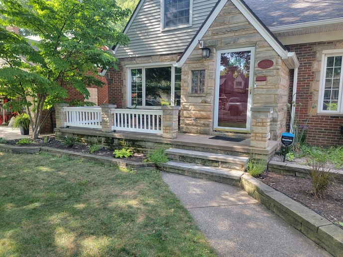 A brick house with a porch and stairs in front of it.