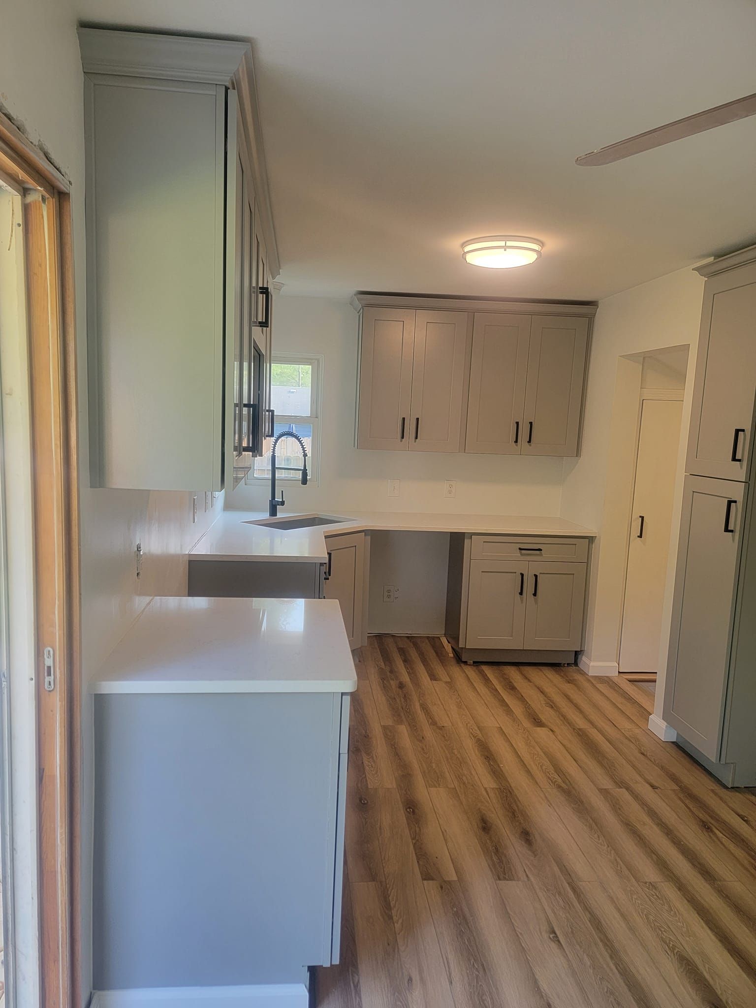 A kitchen with a sink , cabinets , and hardwood floors.