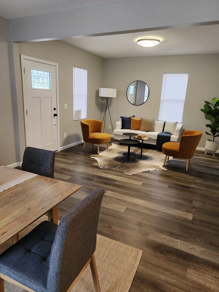 A living room with a couch , chairs , a table and a mirror.