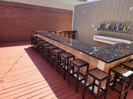A long bar with stools and a brick wall behind it