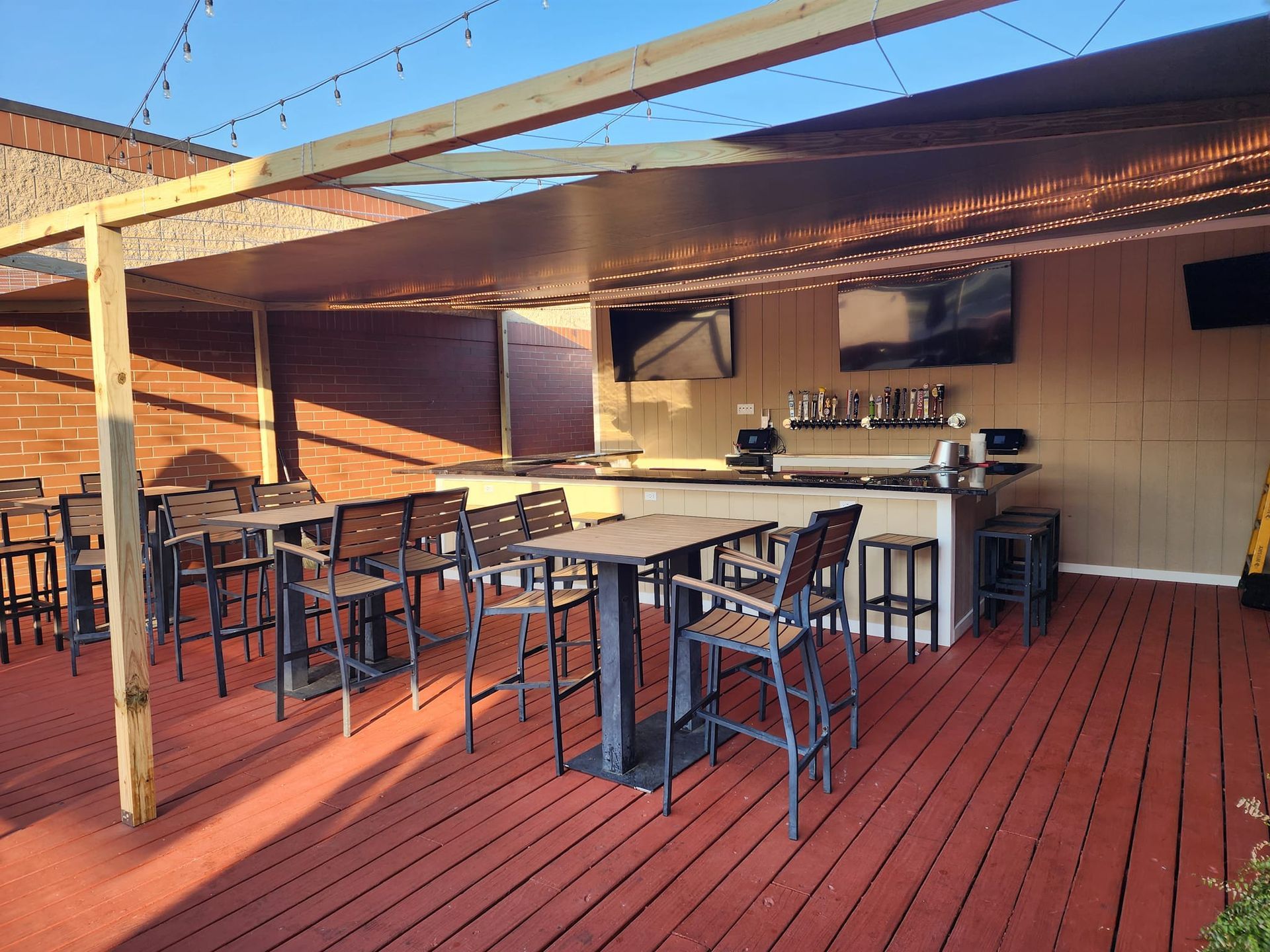 A patio with tables and chairs and a bar under a canopy.