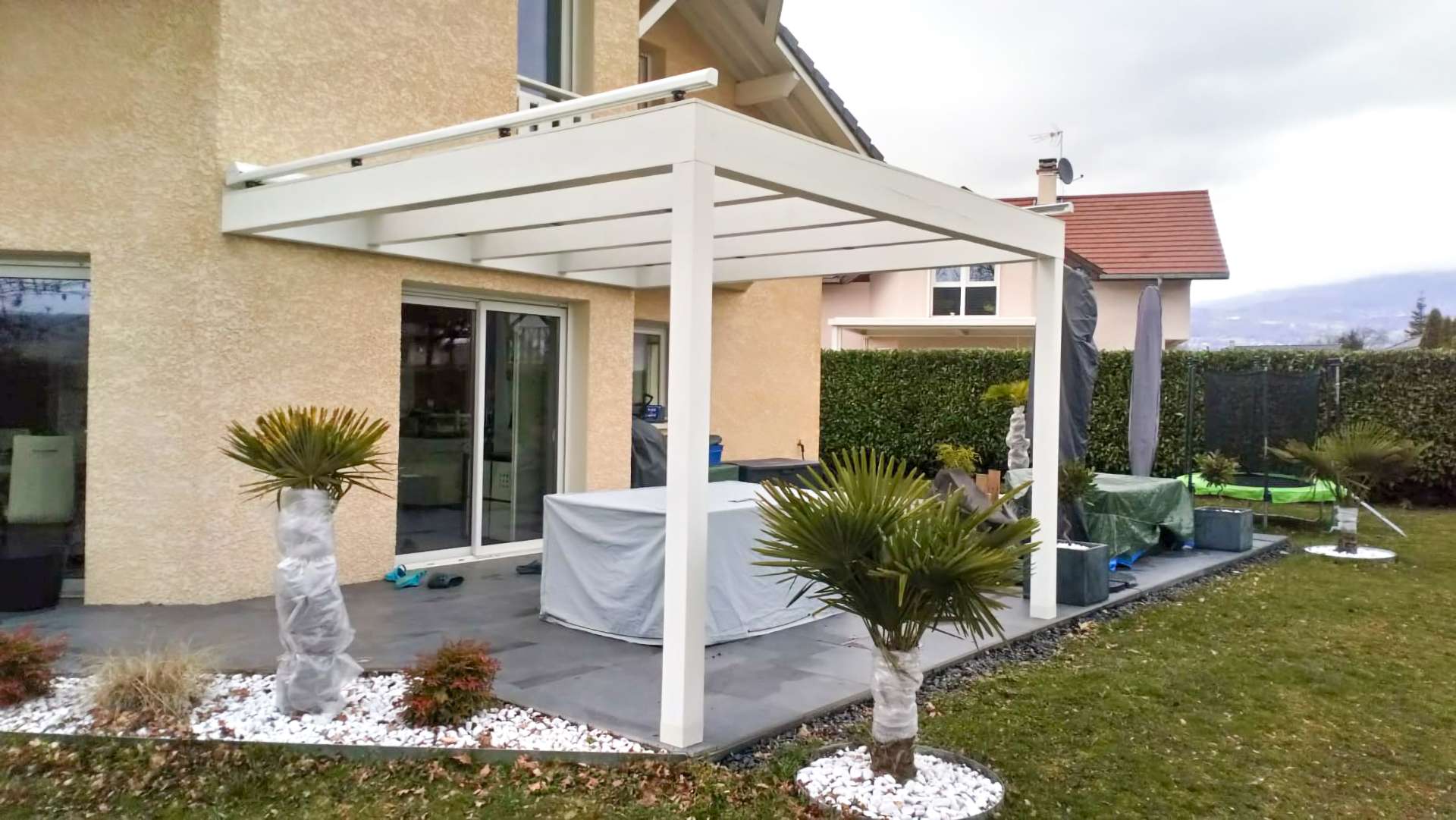 Une maison avec une pergola blanche devant