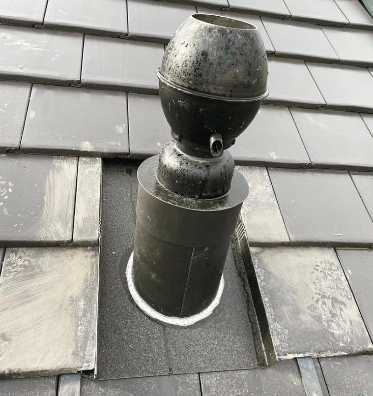 Une cheminée est posée sur un toit en tuiles.