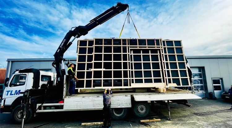 Une grue soulève un gros morceau de bois sur le dessus d'un camion.