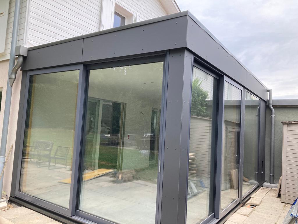 Une maison avec beaucoup de fenêtres et une porte coulissante en verre.