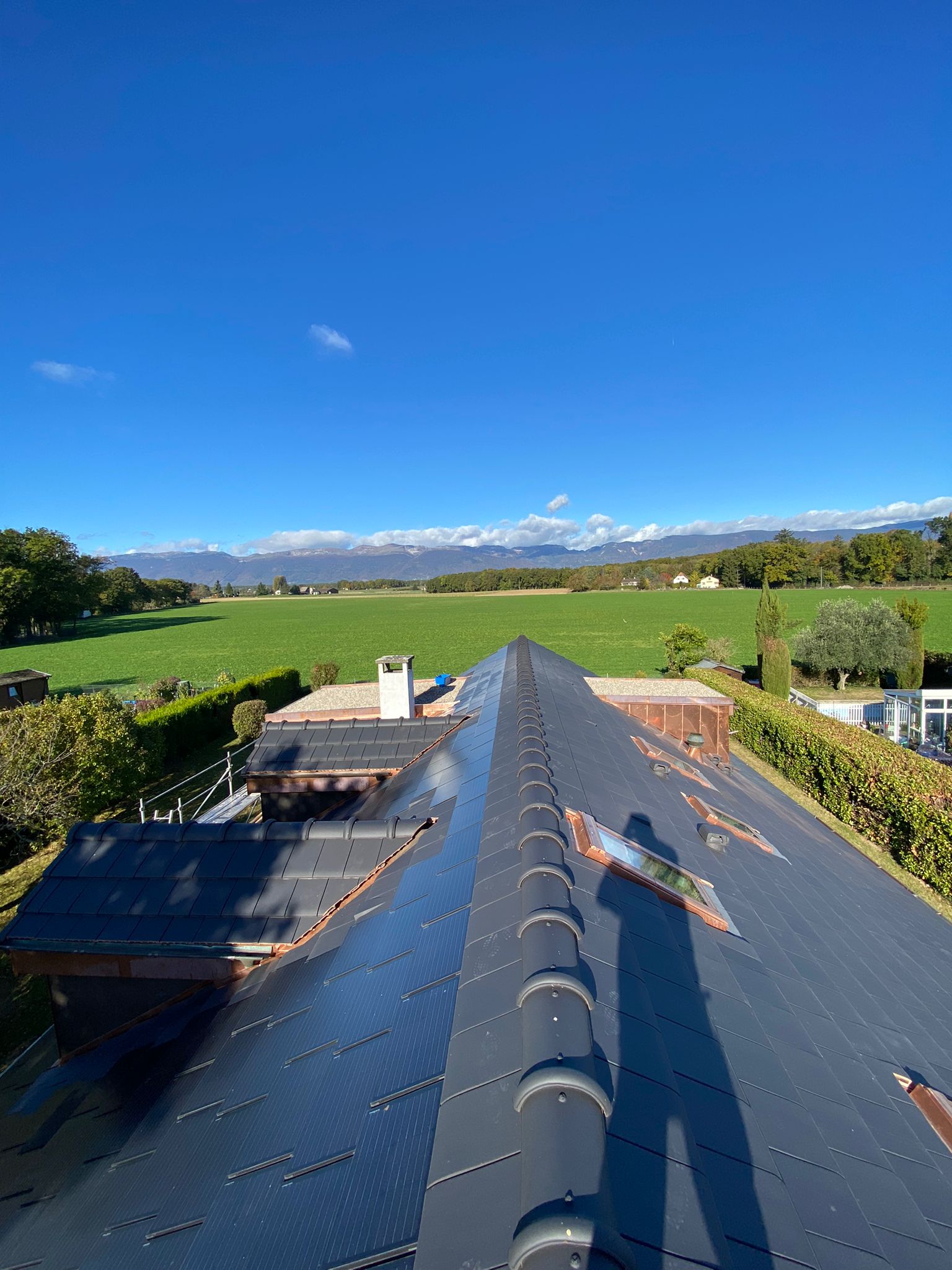 Un toit avec vue sur un champ et des montagnes en arrière-plan.