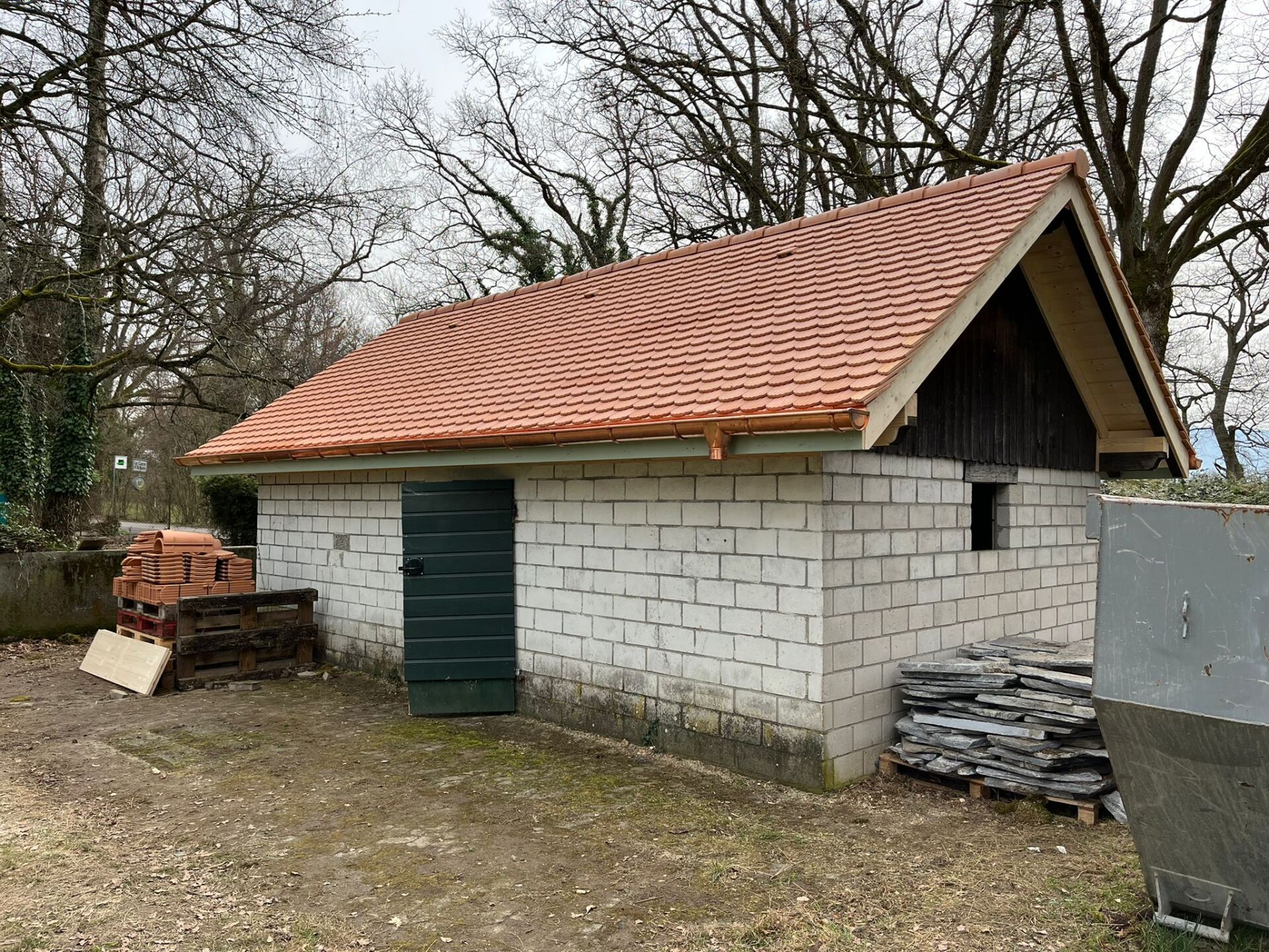 Un petit bâtiment en briques blanches avec un toit de tuiles rouges.
