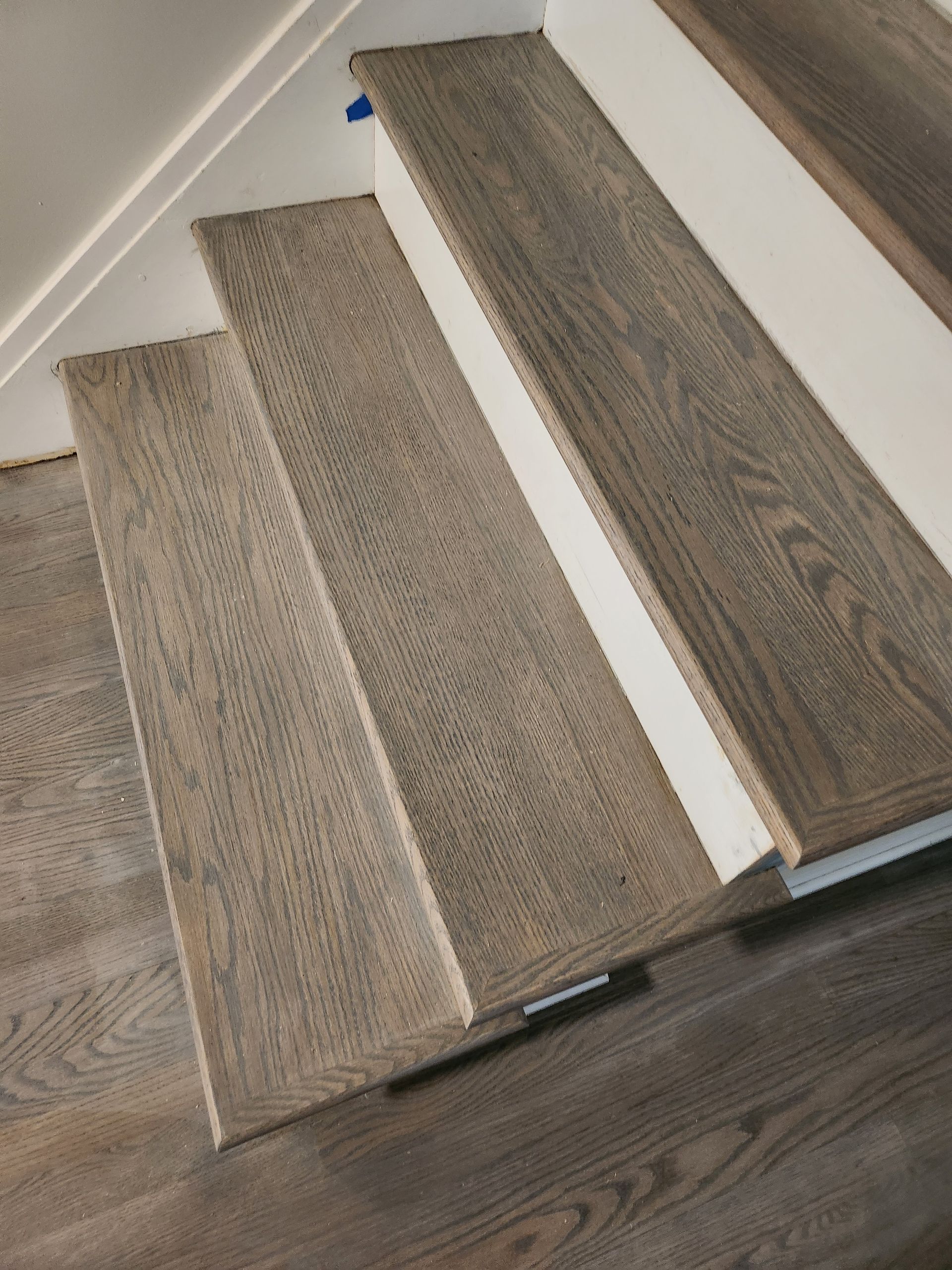 Wooden staircase with gray treads and white risers, viewed from above, descending.